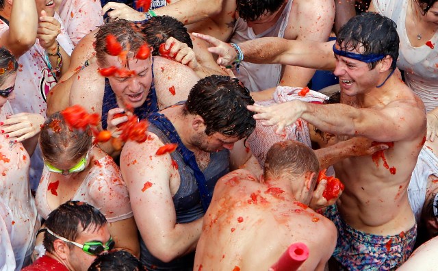 Un grupo de personas se lanza tomates durante la fiesta anual dedicada a este producto, conocida como"Tomatina", en la localidad de Buñol, a 50 kms de Valencia, en España, el 31 de agosto de 2016. Las calles de la localidad levantina se tiñen de rojo con la pulpa del tomate mientras miles de personas se lanzan frutas maduras. Camiones vertieron 160 toneladas de tomates que hicieron las delicias de unos 20.000 participantes, la mayoría extranjeros. (AP Foto/Alberto Saiz)