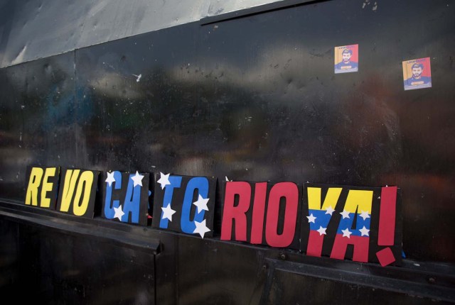 Un cartel en reclamo de la pronta realización del referendo revocatorio del mandato del presidente venezolano Nicolás Maduro es colocado por los manifestantes en la ventana de un vehículo de la policía que bloquea el acceso al Consejo Nacional Electoral en Mérida, Venezuela, el miércoles 7 de septiembre de 2016.  (AP Foto/Fernando Llano)