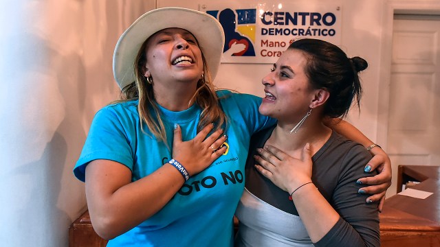 People celebrate after knowing the results of a referendum on whether to ratify a historic peace accord to end a 52-year war between the state and the communist FARC rebels, in Bogota on October 2, 2016. Colombian voters rejected a peace deal with communist FARC rebels Sunday, near-complete referendum results indicated, blasting away what the government hoped would be a historic end to a 52-year conflict. / AFP PHOTO / LUIS ACOSTA