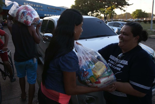 ACOMPAÑA CRÓNICA: BRASIL VENEZUELA BRA04. BOA VISTA (BRASIL), 22/10/2016.- La coordinadora de la Comisión de Migración y Derechos Humanos del estado brasileño de Roraima, Telma Lage, entrega alimentos a inmigrantes venezolanos este jueves, 20 de octubre de 2016, en Boa Vista, estado de Roraima (Brasil). Es venezolana, tiene 20 años, quiere ser traductora y hoy, en una hamaca colgada en un árbol que ha convertido en su casa en la ciudad brasileña de Boa Vista, mece unos sueños que, según aseguró, no serán truncados por "el fracaso de una revolución". "No estoy aquí por política. Lo que me trajo aquí fue el fracaso de unas políticas", dijo a Efe Sairelis Ríos, quien junto a su madre Keila y una decena de venezolanos vive en plena calle, frente a la terminal de autobuses de Boa Vista, una ciudad que en los últimos meses ha recibido unos 2.500 emigrantes de ese país vecino. EFE/Marcelo Sayão