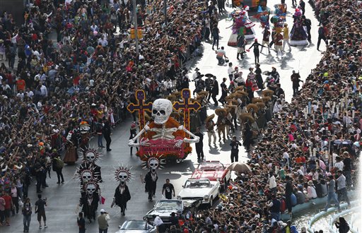 En esta fotografía del 29 de octubre de 2016, una multitud observa el primer desfile del Día de los Muertos en el Paseo de la Reforma en la Ciudad de México. Las películas de Hollywood, los espectáculos de zombies, el Halloween e incluso la política están modificando rápidamente los festejos de México por el Día de los Muertos, que tradicionalmente consistían en reuniones familiares tranquilas en las tumbas de los que han muerto para llevarles música, bebida y conversación. (AP Foto/Marco Ugarte)