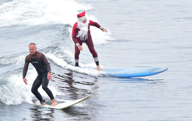 Surfing Santa, Michael Pless, surfs at Seal Beach, California on December 10, 2016, where he runs a surfing school and has every December since in 1990's gone out to surf in his Santa Claus outfit. / AFP PHOTO / Frederic J. BROWN