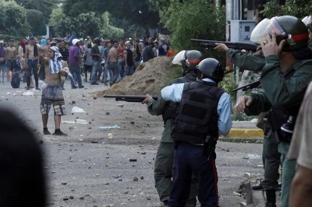 Miembros de la Guardia Nacional enfrentando a manifestantes en una jornada de protesta en La Fría, Venezuela, dic 17, 2016. Soldados patrullaban el lunes las ciudades de Venezuela que se vieron afectadas por disturbios y saqueos durante el fin de semana, y los vecinos resguardaban sus viviendas y comercios con barricadas voluntarias ante la ola de violencia desatada por la crisis de efectivo. REUTERS/Carlos Eduardo Ramirez