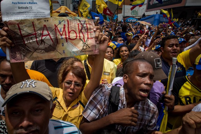 CAR25. CARACAS (VENEZUELA) 14/05/2016.- Una manifestante sostiene un letrero con la palabra "Hambre" en una protesta contra el Gobierno venezolano hoy, sábado 14 de mayo del 2016, en Caracas (Venezuela). Centenares de opositores se concentraron hoy en una de las calles de la capital para exigir a las autoridades electorales que den celeridad a la solicitud de la activación de un referendo revocatorio que permita terminar con el mandato del presidente de Venezuela, el chavista Nicolás Ma duro. EFE/MIGUEL GUTIERREZ