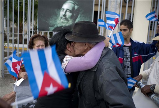 En esta fotografía del domingo 8 de enero de 2017, personas intercambian un abrazo cerca de un retrato del fallecido exgobernante cubano Fidel Castro durante un aniversario de la Revolución en La Habana, Cuba. Los cubanos celebraron el día que Castro ingresó en 1959 en la capital después de que el movimiento rebelde que encabezaba derrocara al dictador Fulgencio Batista. (AP Foto/Ramón Espinosa)