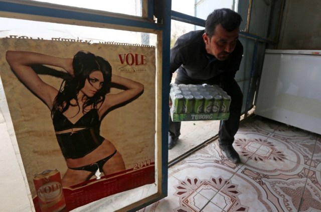 A man brings a case of beer into the alcohol shop of Wissam Ghanem, an Iraqi man from the Yazidi community, in the town of Bashiqa, some 20 kilometres north east of Mosul, on February 17, 2017. Ghanem, who returned to the town of Bashiqa after Kurdish Peshmerga forces retook the town from Islamic State (IS) group jihadists, re-opened his alcohol business which was strictly forbidden under the rule of the Islamists, after finding cans of beer and bottles of spirits in abandoned houses formerly occupied by IS fighters. / AFP PHOTO / SAFIN HAMED