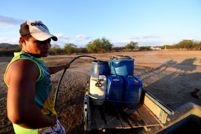 A man fills barrels with water in the rural area of Quixeramobim, in Ceara State, on February 8, 2017, during the worst drought in a century in the Brazilian Northeast.  / AFP PHOTO / EVARISTO SA / TO GO WITH AFP STORY BY CAROLA SOLE