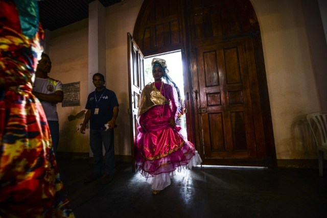 Women dressed as "madamas" attend a mass before the beginning of the Carnival in El Callao, Bolivar state, Venezuela on February 26, 2017. El Callao's carnival was recently named Unesco's Intangible Cultural Heritage of Humanity and is led by the madamas, the pillars of Callaoense identity representing Antillean matrons considered the communicators of values, who dance and wear colourful dresses. / AFP PHOTO / JUAN BARRETO