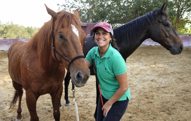 Saudi Dana al-Gosaibi poses with horses during a training session on March 1, 2017, in the Red Sea city of Jeddah. The 35-year-old Saudi horse trainer dreams of opening her own stables to focus on "a more gentle" way of training horses than the standard approach in the male-dominated kingdom. / AFP PHOTO / Amer HILABI