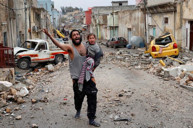 Un hombre llora con su hija en brazos mientras camina desde la parte controlada por el Estado Islámico de Mosul en dirección a los soldados de las fuerzas especiales iraquíes.