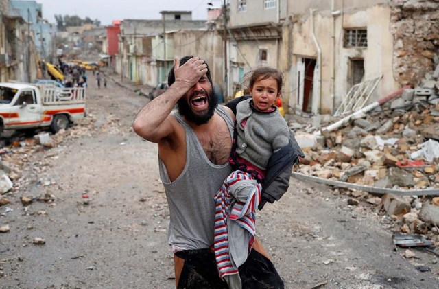 Un hombre llora con su hija en brazos mientras camina desde la parte controlada por el Estado Islámico de Mosul en dirección a los soldados de las fuerzas especiales iraquíes.