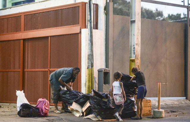  Un hombre y dos niñas escarban en la basura en Caracas AFP PHOTO / JUAN BARRETO 