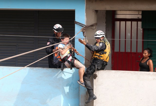 REFILE - CORRECTING NAME OF THE RIVER Rescue workers use a zip line to evacuate a child after the Huaycoloro river overflooded its banks sending torrents of mud and water rushing through the streets in Huachipa, Peru, March 17, 2017. REUTERS/Guadalupe Pardo