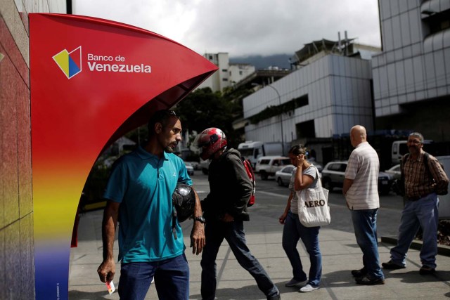 People line up to withdraw cash from an automated teller machine (ATM) outside a Banco de Venezuela branch in Caracas, Venezuela March 14, 2017. Picture taken March 14, 2017. REUTERS/Marco Bello To match Exclusive VENEZUELA-BANKS/