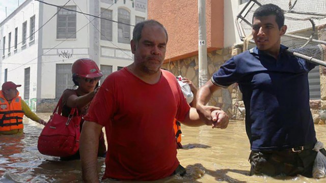 Residents in the city of Piura, 1,000 kilometres north of Lima, wade through water on the streets on March 27, 2017, after nearly 15 hours of rain caused the Piura River to overflow, flooding neighbourhoods in most of the city.  The El Nino climate phenomenon is causing muddy flash floods and rivers to overflow along the entire Peruvian coast, isolating communities and neighborhoods. Most cities face water shortages as water lines have been compromised by mud and debris. / AFP PHOTO / PATRICIA LACHIRA / BEST QUALITY AVAILABLE