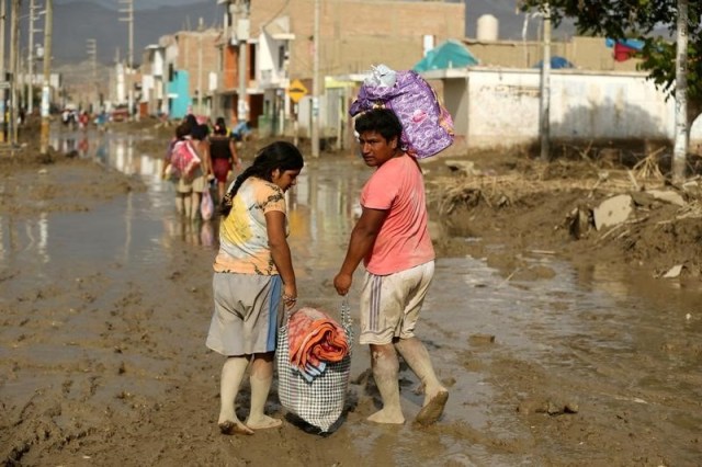 Personas cruzan una calle inundada tras el desborde de ríos por las lluvias torrenciales en Huarmey, Perú. 22 de marzo 2017. El Banco Central de Perú recortó el viernes su proyección de crecimiento económico y no descarta bajar la tasa de interés para ayudar a impulsar la demanda interna, en momentos en que el país sufre sus peores inundaciones en dos décadas. REUTERS/Mariana Bazo