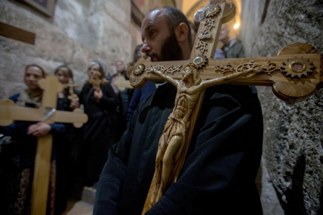 ATS15 JERUSALÉN (ISRAEL) 14/04/2017.- Un fiel carga con una cruz durante una oración en la Iglesia del Santo Sepulcro tras finalizar una procesión de Viernes Santo por la Vía Dolorosa en el casco viejo de Jerusalén (Israel) hoy, 14 de abril de 2017. EFE/Atef Safadi