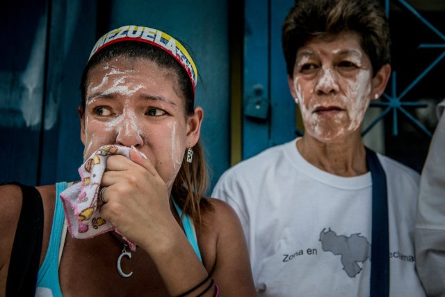 Manifestantes se recuperan de los gases lacrimógenos lanzados por los cuerpos de seguridad durante una marcha multitudinaria, el miércoles en Caracas. Credit Meridith Kohut para The New York Times