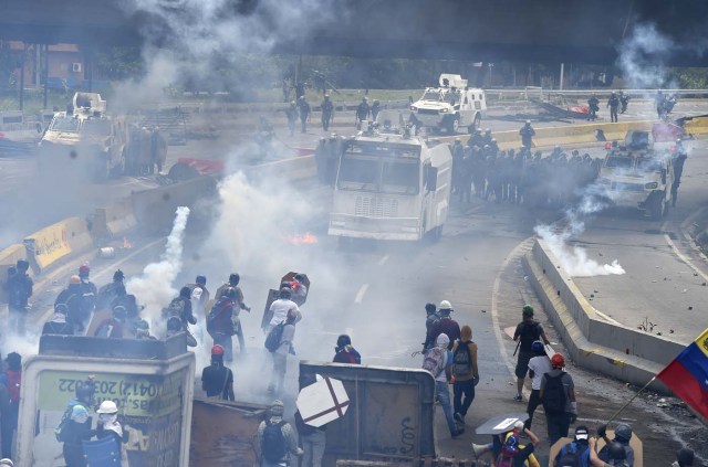 Opposition activists clash with riot police during a protest against Venezuelan President Nicolas Maduro, in Caracas on May 3, 2017. Venezuela's angry opposition rallied Wednesday vowing huge street protests against President Nicolas Maduro's plan to rewrite the constitution and accusing him of dodging elections to cling to power despite deadly unrest. / AFP PHOTO / JUAN BARRETO