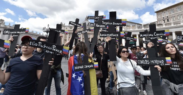 Members of the Venezuelian community hold black crosses with names of victims of clashes with police during protests against Venezuela's President Nicolas Maduro, on May 7, 2017  at St Peter's square before the Regina Coeli prayer of Pope Francis in Vatican. Pope Francis last week made a heartfelt appeal for "negotiated solutions" to end the violence in crisis-torn Venezuela for the sake of an "exhausted population".  The death toll since April -- when the protests intensified after Maduro's administration and the courts stepped up efforts to undermine the opposition -- is at least 36, according to prosecutors, with hundreds more injured. / AFP PHOTO / TIZIANA FABI