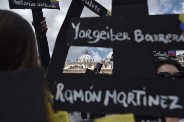 Members of the Venezuelian community hold black crosses with names of victims of clashes with police during protests against Venezuela's President Nicolas Maduro, on May 7, 2017  at St Peter's square before the Regina Coeli prayer of Pope Francis in Vatican. Pope Francis last week made a heartfelt appeal for "negotiated solutions" to end the violence in crisis-torn Venezuela for the sake of an "exhausted population".  The death toll since April -- when the protests intensified after Maduro's administration and the courts stepped up efforts to undermine the opposition -- is at least 36, according to prosecutors, with hundreds more injured. / AFP PHOTO / TIZIANA FABI