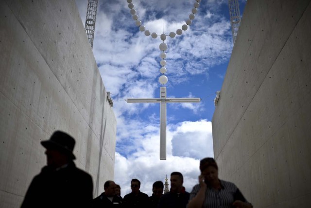 People walk under a giant rosary hanging at Fatima Sanctuary in Fatima, central Portugal, on May 12, 2017.   Two of the three child shepherds who reported apparitions of the Virgin Mary in Fatima, Portugal, one century ago, will be declared saints on May 13, 2017 by Pope Francis. The canonisation of Jacinta and Francisco Marto will take place during the Argentinian pontiff's visit to a Catholic shrine visited by millions of pilgrims every year. / AFP PHOTO / PATRICIA DE MELO MOREIRA