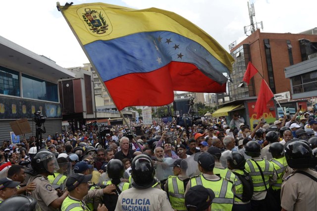 Opposition activists confront riot police during a protest against the government in Caracas on May 12, 2017. Daily clashes between demonstrators -who blame elected President Nicolas Maduro for an economic crisis that has caused food shortage- and security forces have left 38 people dead since April 1. Protesters demand early elections, accusing Maduro of repressing protesters and trying to install a dictatorship. / AFP PHOTO / FEDERICO PARRA