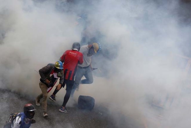 A demonstrator runs away from tear gas during a rally called by health care workers and opposition activists against Venezuela's President Nicolas Maduro in Caracas, Venezuela May 22, 2017. REUTERS/Marco Bello