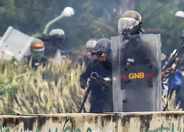 A member of the National Guard (C) holds a semiautomatic pistol during clashes with opposition activists demonstrating against the government of President Nicolas Maduro along the Francisco Fajardo highway in Caracas on June 19, 2017. A 17-year-old activist died on June 20, 2017 from a shot allegedly fired by a National Guard during clashes with opposition demonstrators on the eve, when six other persons were also wounded by live bullets. / AFP PHOTO / Juan BARRETO / CROPPED VERSION