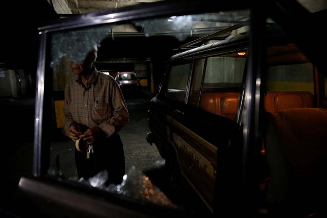 A man stands in a garage and next to a car with a shattered window after opposition supporters and security forces clashed in and outside the building on Tuesday according to residents, in Caracas, Venezuela June 14, 2017. REUTERS/Ivan Alvarado