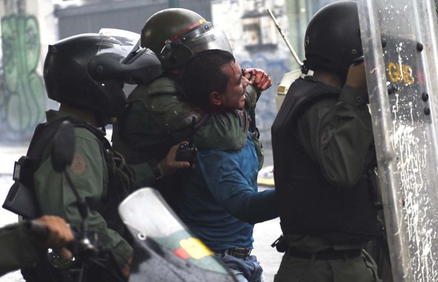 An anti-government activist is arrested during clashes in Caracas on July 28, 2017. Protesters took over streets in Caracas on Friday in a show of defiance to President Nicolas Maduro, as the crisis gripping Venezuela turned deadlier ahead of a controversial weekend election that has earned international scorn. / AFP PHOTO / CARLOS BECERRA