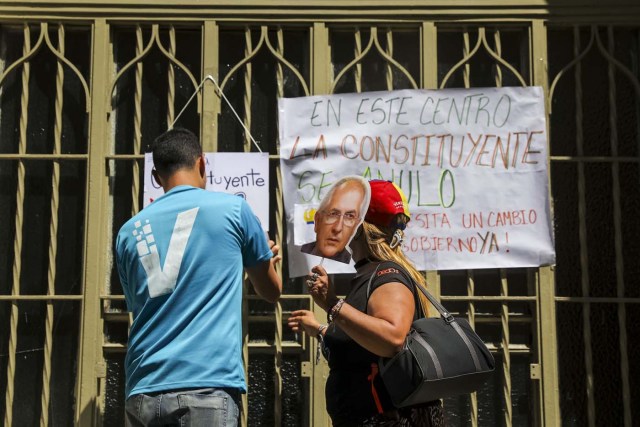 CAR06. CARACAS (VENEZUELA), 24/07/2017.- Una pareja pega carteles en rechazo a la Asamblea Constituyente hoy, lunes 24 de julio de 2017, en un colegio electoral de Caracas (Venezuela). Venezuela inicia hoy la semana decisiva para la elección de la Asamblea Nacional Constituyente convocada por el presidente, Nicolás Maduro, con los oficialistas entrando en la recta final de su campaña en medio de protestas y llamados a paro de los opositores en rechazo a esos comicios. EFE/Miguel Gutiérrez