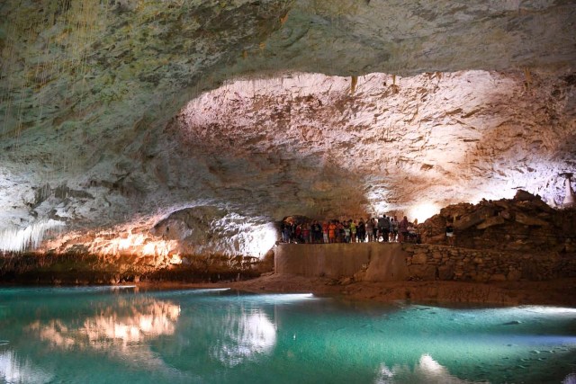 People visit the natural cave of Choranche, in the Vercors region near Grenoble, on August 3, 2017. Since the beginning of the heat wave, there has been an increase of at least 10 percent in the number of cave visitors, looking for beautiful natural sites, but also for underground freshness with temperatures around 15 Degrees Celsius. / AFP PHOTO / JEAN-PIERRE CLATOT