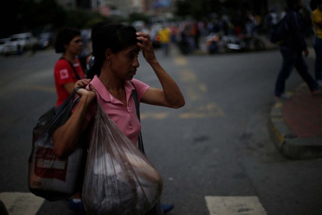 A woman carries shopping bags as she walks along a street in Caracas, Venezuela, August 9, 2017. REUTERS/Andres Martinez Casares