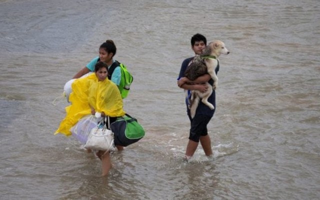 Una familia carga sus pertenencias y su perro mientras caminan por Tidwell Road, en la zona este de Houston, Texas // FOTO Reuters