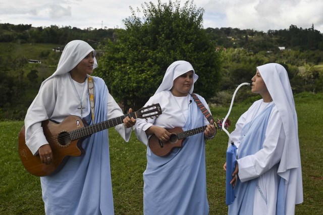 Nun Maria Valentina de los Angeles (C) alongside fellow nuns Alejandra (L) and Ana Maria, of the ?Comunicadoras Eucaristicas del Padre Celestial? (Eucharistic Communicators of the Celestial Father) congregation, play instruments during the recording of a video at a convent in the outskirts of Cali, Colombia, on July 17, 2017. Nun Maria Valentina de los Angeles ?who wears tennis shoes, raps and already participated in a reality show- will see her dream of singing to Pope Francis come true during his visit to Colombia. / AFP PHOTO / Luis ROBAYO / TO GO WITH AFP STORY BY RODRIGO ALMONACID