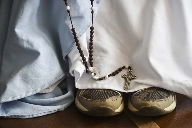 A fellow nun of Maria Valentina de los Angeles, of the ?Comunicadoras Eucaristicas del Padre Celestial? (Eucharistic Communicators of the Celestial Father) congregation, holds a rosary during her prayer at a convent in the outskirts of Cali, Colombia, on July 17, 2017. Nun Maria Valentina de los Angeles ?who wears tennis shoes, raps and already participated in a reality show- will see her dream of singing to Pope Francis come true during his visit to Colombia. / AFP PHOTO / Luis ROBAYO / TO GO WITH AFP STORY BY RODRIGO ALMONACID