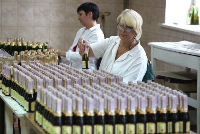 An employee checks bottles as she works on the production line in the "Artwinery" winery firm in the eastern Ukrainian city of Bakhmut on July 12, 2017. The winery is located in a government-held town just two dozen kilometres (15 miles) from the frontline in Ukraine's low-level war, where the army and Russian-backed rebels continue to lob deadly artillery barrages at each other. The town spent around a month under rebel control in 2014, and in 2015 the frontline was so close that the town came under rebel shelling. But despite more than three years of fighting that has claimed some 10,000 lives, Nasyrov's employer, Artwinery, has never stopped production. / AFP PHOTO / Aleksey FILIPPOV