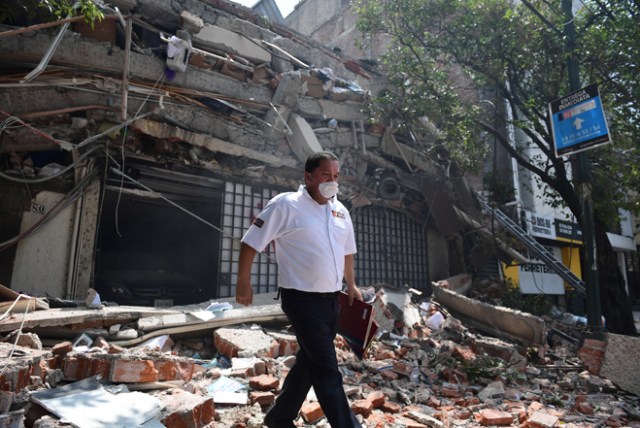 A security guard walks over debris of a building which collapsed during a quake in Mexico City on September 19, 2017. A powerful earthquake shook Mexico City on Tuesday, causing panic among the megalopolis' 20 million inhabitants on the 32nd anniversary of a devastating 1985 quake. The US Geological Survey put the quake's magnitude at 7.1 while Mexico's Seismological Institute said it measured 6.8 on its scale. The institute said the quake's epicenter was seven kilometers west of Chiautla de Tapia, in the neighboring state of Puebla. / AFP PHOTO / Ronaldo SCHEMIDT