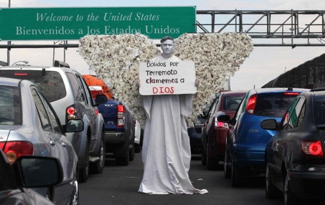 A member of Christian church Salmo 100 dressed as an angel shows a message addressed to the victims of the last earthquake in Mexico City, in front of drivers crossing the Cordova-Americas International Bridge between Ciudad Juarez, Chihuahua state and El Paso, Texas on September 23, 2017 in Ciudad Juárez, Chihuahua, Mexico. / AFP PHOTO / HÉRIKA MARTÍNEZ