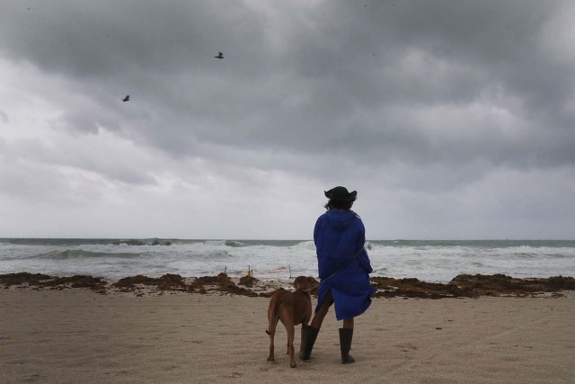 MIAMI BEACH, FL - SEPTEMBER 09: Monica Gutierrez and Tyson look out at the storm clouds and churning ocean as Hurricane Irma approaches on September 9, 2017 in Miami Beach, Florida. Florida is in the path of the Hurricane which may come ashore at category 4.   Joe Raedle/Getty Images/AFP