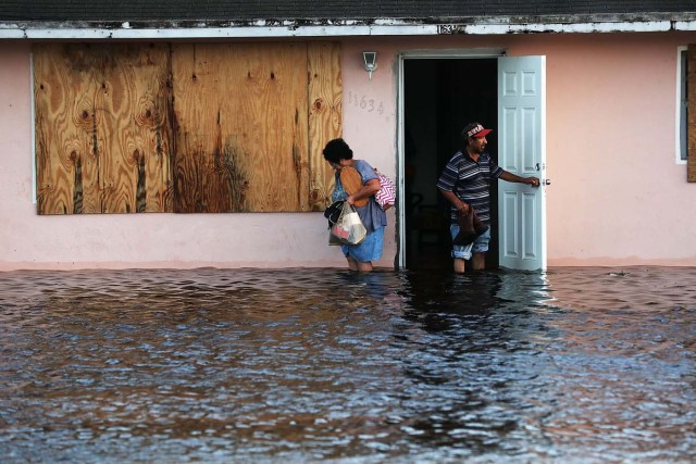 BONITA SPRINGS, FL - SEPTEMBER 11: A couple leave their flooded home the morning after Hurricane Irma swept through the area on September 11, 2017 in Fort Myers, Florida. Hurricane Irma made another landfall near Naples yesterday after inundating the Florida Keys. Electricity was out in much of the region with localized flooding. Spencer Platt/Getty Images/AFP