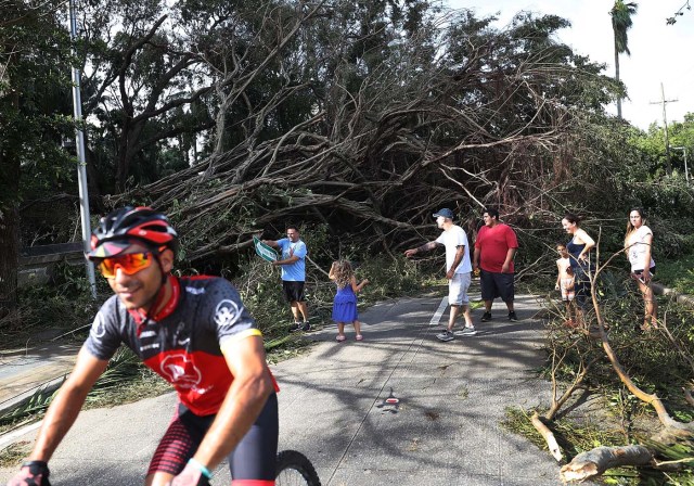 MIAMI, FL - SEPTEMBER 11: People move around branches and trees that were downed when hurricane Irma passed through the area on September 11, 2017 in Miami, Florida. Florida took a direct hit from the Hurricane. Joe Raedle/Getty Images/AFP