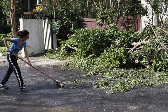 MIAMI, FL - SEPTEMBER 11: Ann Gil sweeps into a pile branches that were downed when hurricane Irma passed through the area on September 11, 2017 in Miami, Florida. Florida took a direct hit from the Hurricane. Joe Raedle/Getty Images/AFP