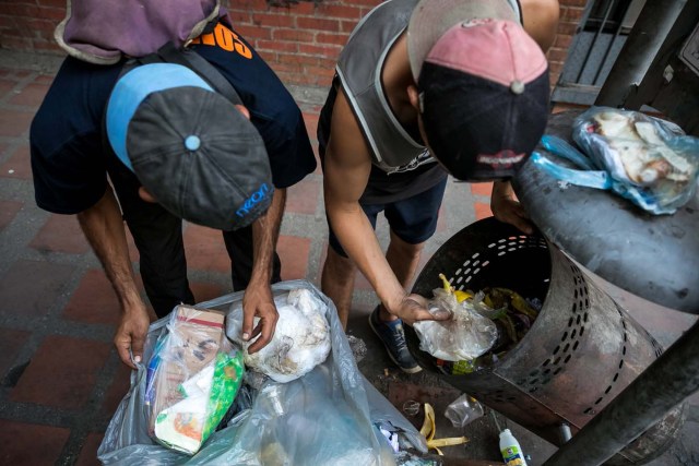 ACOMPAÑA CRÓNICA: VENEZUELA CRISIS. CAR04. CARACAS (VENEZUELA), 25/09/2017.- Fotografía fechada el 20 de septiembre de 2017 que muestra a dos hombres mientras hurgan en una basura en busca de comida en una calle de Caracas (Venezuela). En las calles de Caracas deambulan cada vez más niños y de menos edad. Se trata, según analistas y activistas de derechos humanos, de una nueva oleada de pequeños que prácticamente han abandonado sus hogares, aunque esta vez la razón es una sola: "La falta de comida en sus casas". EFE/Miguel Gutiérrez