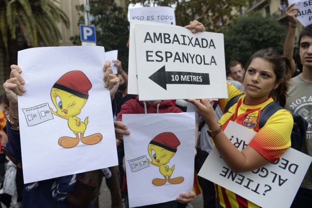 A protester holds a sign reading "Spanish Embassy, 10 metres" as people gather during a general strike in Barcelona called by Catalan unions on October 3, 2017. Large numbers of Catalans are expected to observe a general strike today to condemn police violence at a banned weekend referendum on independence, as Madrid comes under growing international pressure to resolve its worst political crisis in decades. / AFP PHOTO / Josep LAGO