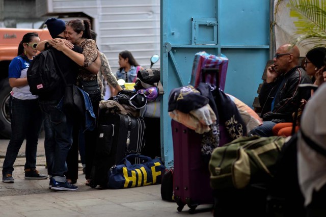 People bid farewell to relatives before boarding a bus at a station in Caracas on October 11, 2017 as scores of disappointed Venezuelans who see no end to the crisis choose to leave the country. Venezuela, which holds regional elections on October 15, is a country at the top of the Latin American continent that is in deep economic and political crisis. / AFP PHOTO / Federico PARRA