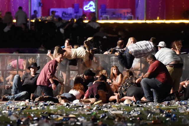 LAS VEGAS, NV - OCTOBER 01: People scramble for shelter at the Route 91 Harvest country music festival after apparent gun fire was heard on October 1, 2017 in Las Vegas, Nevada. A gunman has opened fire on a music festival in Las Vegas, leaving at least 20 people dead and more than 100 injured. Police have confirmed that one suspect has been shot. The investigation is ongoing.   David Becker/Getty Images/AFP