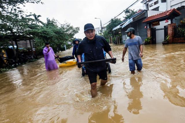 Residentes caminan por las calles inundadas de Hoi An (Vietnam) hoy, 6 de noviembre de 2017. Al menos 27 personas murieron y otras 22 se encuentran desaparecidas debido a las fuertes lluvias e inundaciones causadas por el tifón Damrey en la zona central de Vietnam. EFE/ Wallace Woon