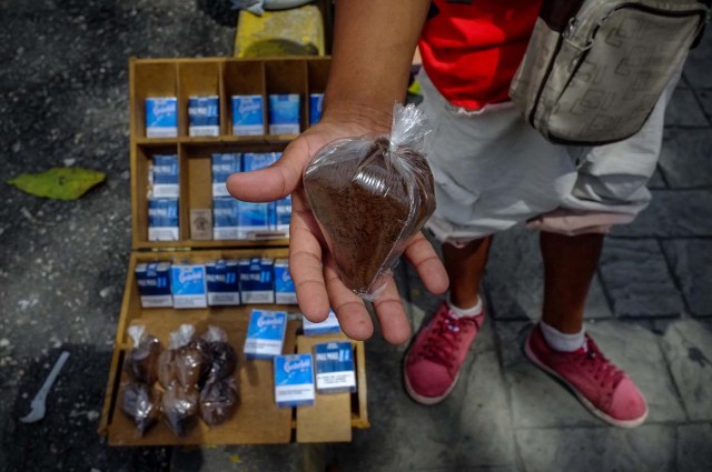 ACOMPAÑA CRÓNICA: VENEZUELA CRISIS - CAR007. CARACAS (VENEZUELA), 19/11/2017.- Fotografía del 17 de noviembre de 2017, que muestra a un vendedor mientras sostiene una bolsa de café en un puesto de venta informal en una calle de Caracas (Venezuela). Venezuela es el país del mundo con mayores reservas de petróleo, pero el empobrecimiento de sus habitantes les ha abocado a comprar cucharadas de comida para intentar burlar una escasez de alimentos que se ha agravado en los últimas semanas, cuando la economía entró en una espiral hiperinflacionaria. Productos de consumo diario como el café, la harina, la leche y el azúcar son ofrecidos ahora en bolsitas que pesan entre 50 y 150 gramos, cuyos precios suben cada día en los puestos ambulantes de los barrios populares al margen de las regulaciones impuestas por el Gobierno de Nicolás Maduro. EFE/Cristian Hernández